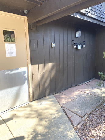 Exterior view of a building entrance with a wooden door and wall.