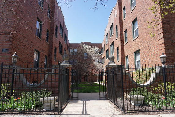 Front view of a multi-story brick apartment building with gate.
