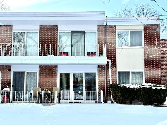 Front view of a two-story brick building with balconies and large windows.