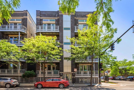 Front view of a multi-story modern apartment building with balconies and large windows.