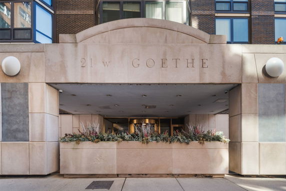 Front view of a building entrance with stone facade and floral decoration.