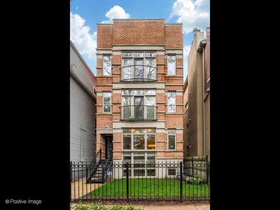 Front view of a multi-story brick building with large windows and balconies.
