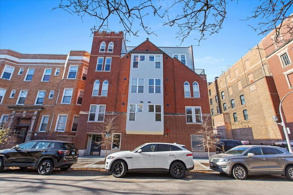 Front view of a multi-story brick building with arched windows.