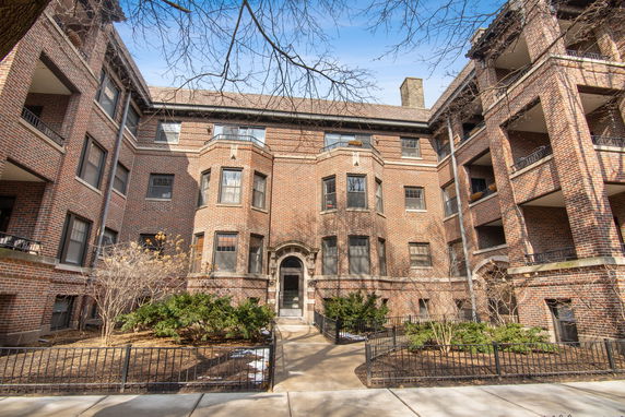 Front view of a multi-story brick apartment building with a central entrance.
