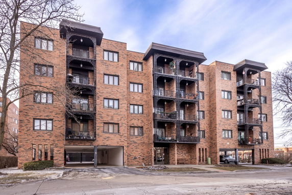 Front view of a multi-story brick apartment building with balconies.