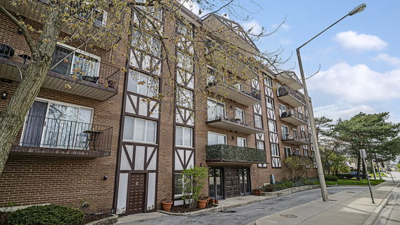 Front view of a multi-story apartment building with balconies and brick facade.