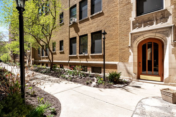 Front view of a multi-story brick building with arched wooden entrance.