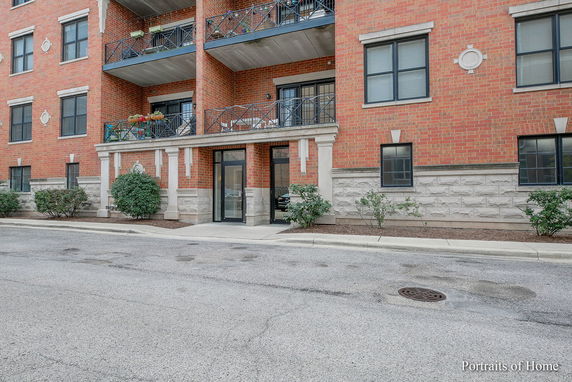 Front view of a multi-story residential building with balconies and brick facade.