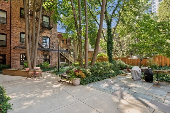 View of a brick apartment building courtyard with trees and outdoor furniture.