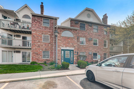 Front view of a multi-story brick apartment building with balconies.