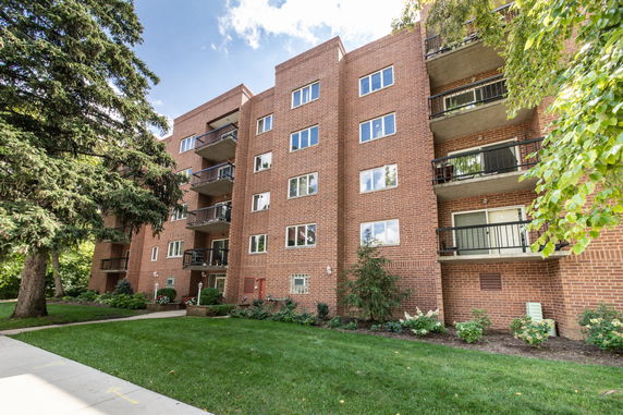 Front view of a multi-story brick apartment building with balconies.