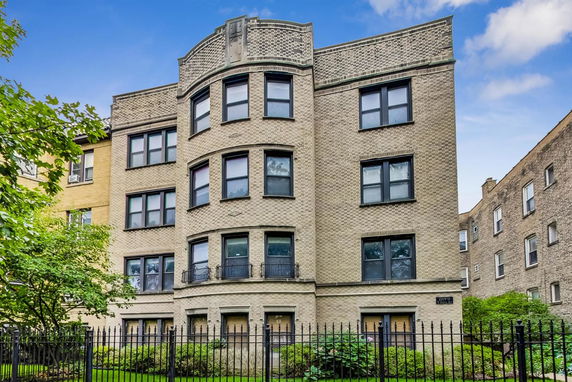 Front view of a multi-story brick apartment building with multiple large windows.