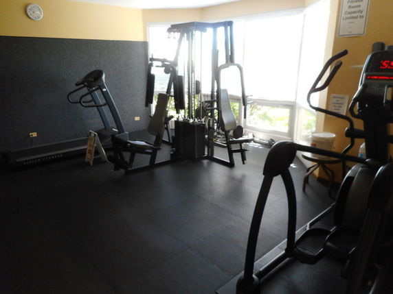 Room with exercise equipment including a treadmill and elliptical machine.