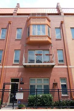 Front view of a multi-story brick building with a balcony.