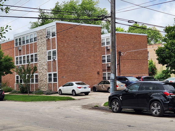 Front view of a three-story brick apartment building with multiple windows.