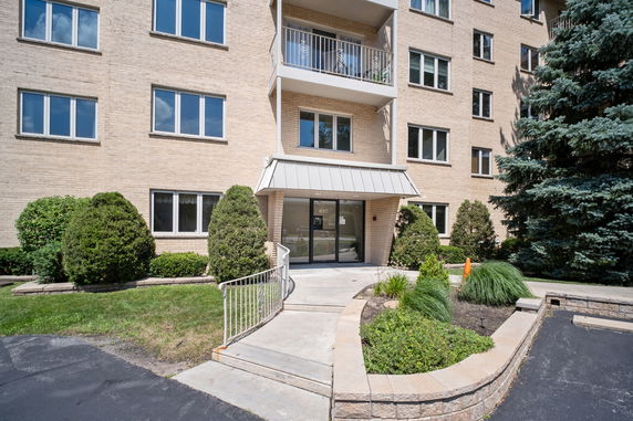 Front view of a multi-story apartment building with a glass entrance.