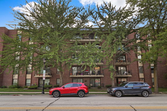Front view of a multi-story brick residential building with balconies.