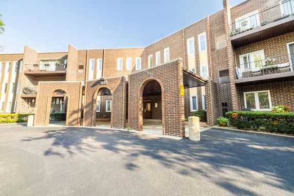Front view of a multi-story building with brick facade and balconies.