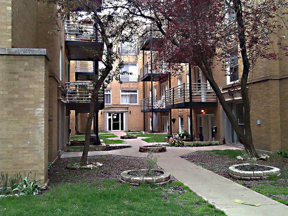 Courtyard view of an apartment complex with green areas and trees.
