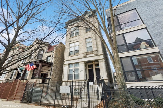 Front view of a three-story residential building with a gated entrance.