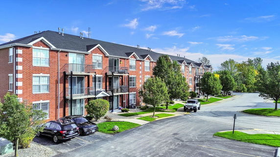 Front view of a multi-story apartment building with brick facade and balconies.