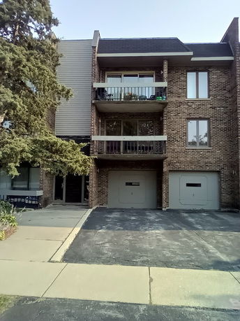 Front view of a multi-story building with a brick facade and two garages.