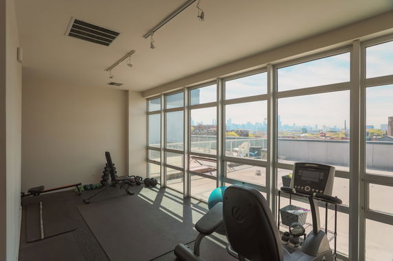 Room with gym equipment and large windows on a high floor.