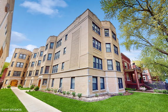 Front view of a four-story apartment building with light brick exterior.