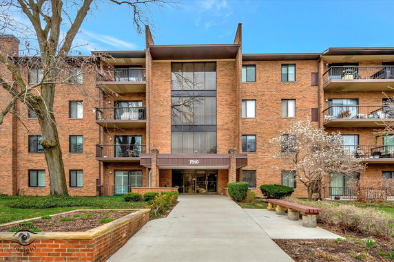Front view of a multi-story brick apartment building with balconies.