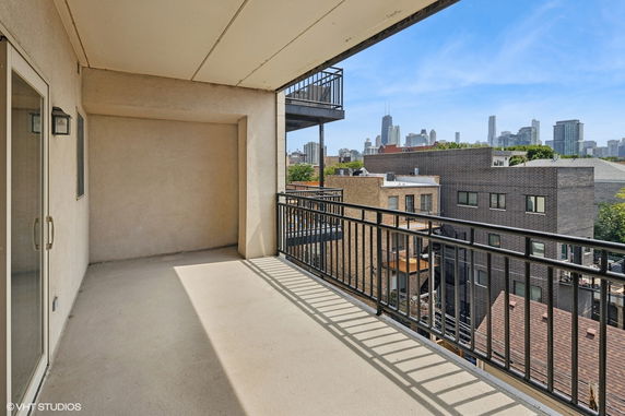 View from a balcony overlooking buildings and a city skyline in the distance.