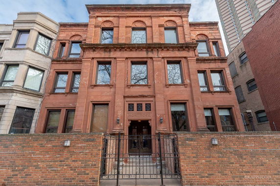 Front view of a historic multi-story building with brick facade and decorative architectural details.