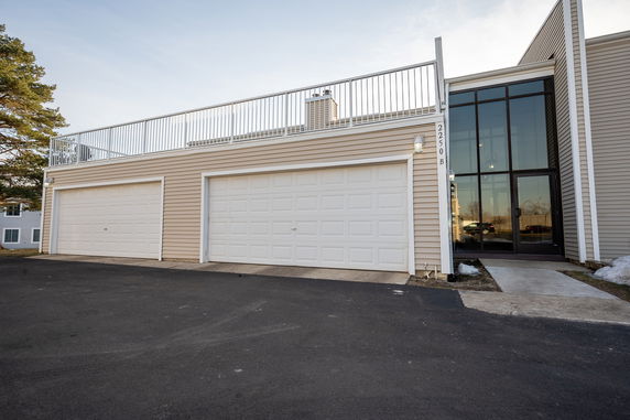 Front view of a building with double garage doors and a rooftop railing.