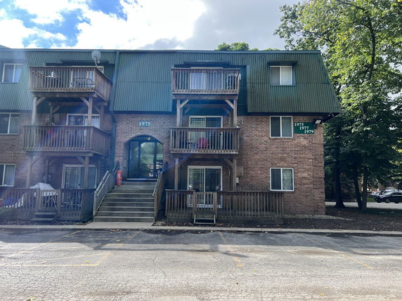 Front view of a multi-story brick residential building with balconies.