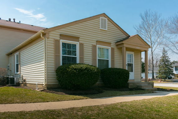 Front view of a single-story house with beige siding and a small porch.