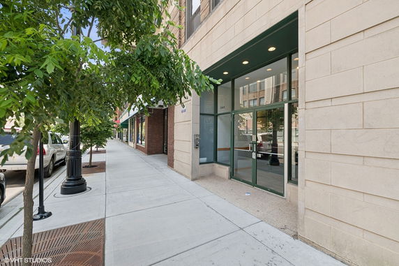 Front view of a building entrance on a sidewalk with glass doors.