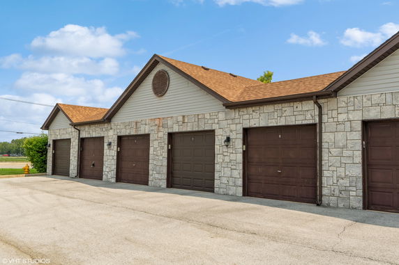 Front view of a multi-garage building with stone facade and gable roof.