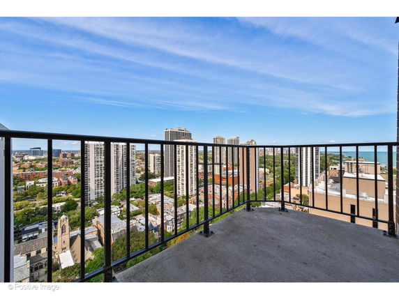 Panoramic view from a balcony overlooking city buildings and a distant body of water.