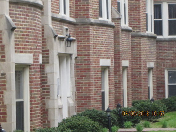 Front view of a red brick building with multiple windows and stone accents.