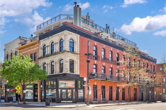 Front view of a multi-story brick building on a street corner.