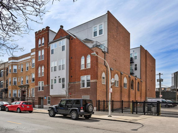 Front view of a multi-story brick building with arched windows.