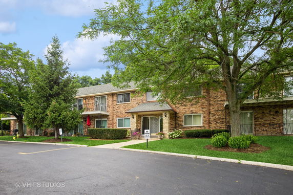 Front view of a two-story brick building with a central entrance and balconies.