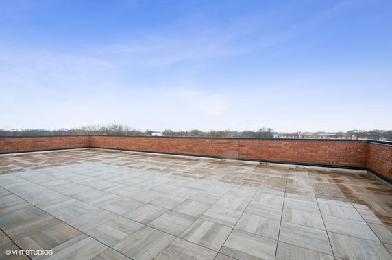 Rooftop with tiled flooring and brick walls, under a clear blue sky.