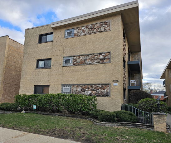 Front view of a multi-story brick building with stone accents.