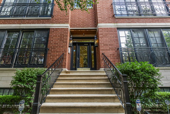 Front view of a multi-story brick building with metal railings and steps leading to the entrance.