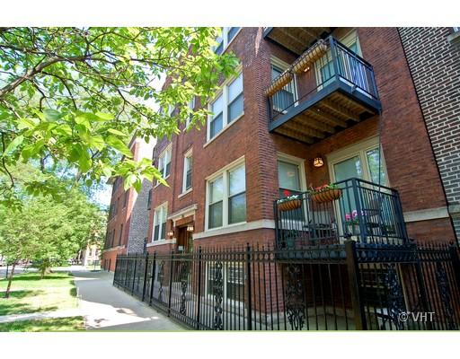 Front view of a multi-story brick building with balconies and a fenced entrance.