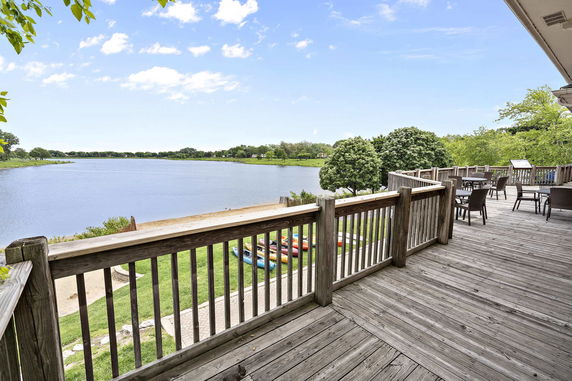 Panoramic view from a wooden deck overlooking a large body of water and surrounding greenery.