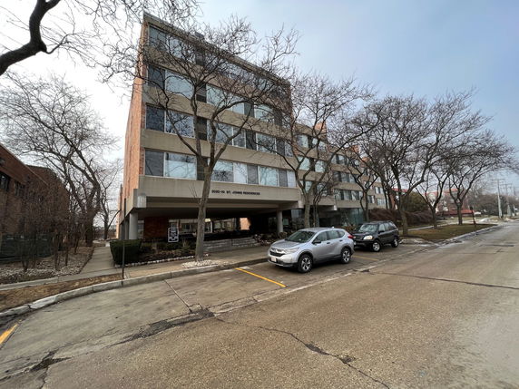 Front view of a multi-story residential building with parking spaces in front.