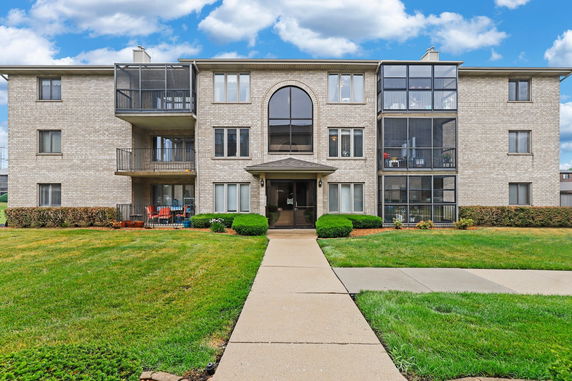 Front view of a multi-story brick apartment building with balconies.