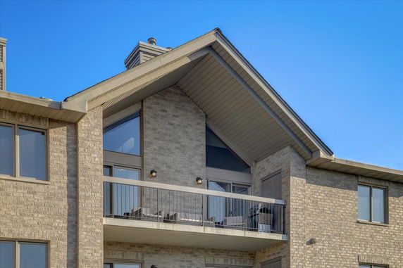 Front view of a modern residential building with a sloped roof and balcony.