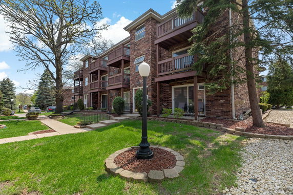 Front view of a multi-story brick residential building with balconies.